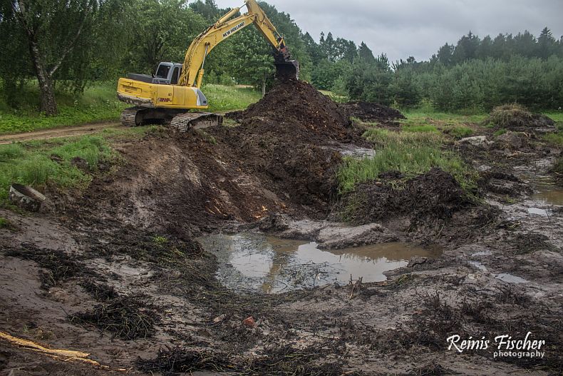 Excavator digging pond from the road side