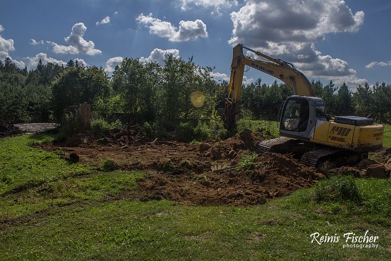Excavator taking down collapsed cowshed
